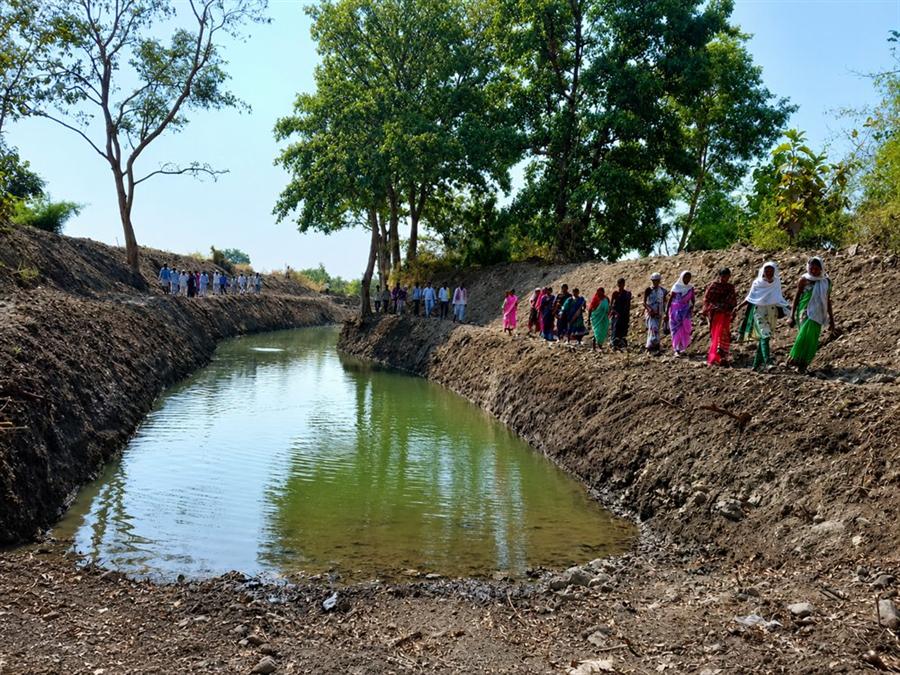 Villagers gathered along a newly excavated Doha structure filled with water